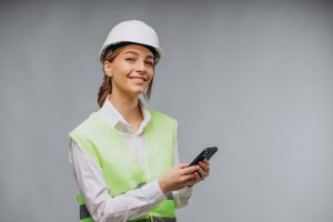 Business woman wearing vest and helmet talking on the phone